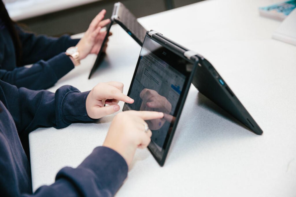 A student writing notes with a stylus on a touchscreen Acer Chromebook in class