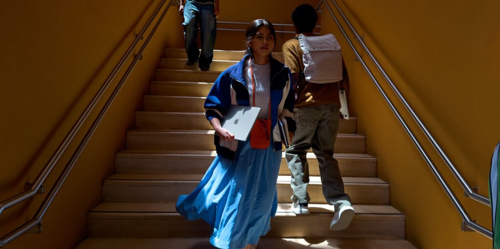 Student carrying a slim Apple MacBook Air in a backpack while walking on campus'.